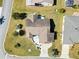 Overhead shot showcasing a home with a brown roof and stone patio, surrounded by lush, green landscaping at 909 Abaco Path, The Villages, FL 32163