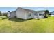 Expansive backyard with well-maintained lawn, a patio with grill, and mature landscaping at 909 Abaco Path, The Villages, FL 32163