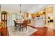 Open concept dining room with wood floors, chandelier, and a partial view of the kitchen at 909 Abaco Path, The Villages, FL 32163
