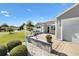 Close up of a home's front yard with a well-manicured lawn, shrubs, and a cozy front patio area at 909 Abaco Path, The Villages, FL 32163