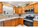 Bright kitchen features wood cabinets, stainless steel appliances, and a double sink under the window at 909 Abaco Path, The Villages, FL 32163