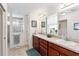 Bathroom featuring double sinks, wooden cabinetry, and a glass block shower at 10105 Ketch Kay Ln, Oxford, FL 34484