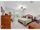 Bright bedroom with neutral carpet features ceiling fan, side tables and natural light at 10105 Ketch Kay Ln, Oxford, FL 34484