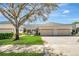 Charming home featuring a three-car garage, manicured lawn, and mature tree in a serene setting at 1037 Green Gate Blvd, Groveland, FL 34736