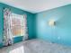 Bright bedroom features a large window, soft carpet, and calming blue walls at 1041 Eastbrook Ave, Deltona, FL 32738