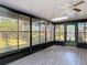 Enclosed sunroom features wood tile flooring, a ceiling fan and views of the back yard at 1041 Eastbrook Ave, Deltona, FL 32738