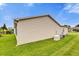 Clean exterior side view of home featuring a well-maintained lawn, generator, and AC unit at 1106 Blythe Way, The Villages, FL 32162