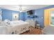 Well-lit bedroom with a TV, white dresser, and blue walls at 1112 Forest Ln, Tavares, FL 32778