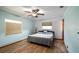 Cozy bedroom with a ceiling fan and a window, featuring light blue walls and wood floors at 119 E Croton Way, Howey In The Hills, FL 34737