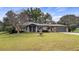 Charming single-story home with a manicured lawn, brick facade, two-car garage, and a welcoming fountain at 119 E Croton Way, Howey In The Hills, FL 34737