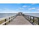 Scenic view of a long wooden pier extending over tranquil waters to a covered shelter on a sunny day at 119 E Croton Way, Howey In The Hills, FL 34737