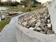 Lakeside backyard view with concrete path, decorative rock wall and dock with alligator decoration at 12066 Se 60Th Avenue Rd, Belleview, FL 34420