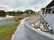 View of a backyard, including lake, dock, and rock retaining wall at 12066 Se 60Th Avenue Rd, Belleview, FL 34420