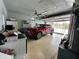 Spacious garage featuring speckled floor, ceiling fan, and housing a red car, providing ample parking and storage at 12066 Se 60Th Avenue Rd, Belleview, FL 34420