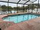 Enclosed swimming pool features brick trim, lake view, and screened enclosure at 12066 Se 60Th Avenue Rd, Belleview, FL 34420