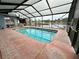 Enclosed in-ground swimming pool features a lake view, brick trim, and screened enclosure at 12066 Se 60Th Avenue Rd, Belleview, FL 34420