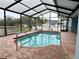 Enclosed in-ground swimming pool features a lake view, brick trim, and screened enclosure at 12066 Se 60Th Avenue Rd, Belleview, FL 34420