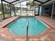 Enclosed swimming pool features brick trim, multiple access ladders, and screened enclosure at 12066 Se 60Th Avenue Rd, Belleview, FL 34420