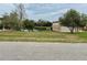 A long view of a well-manicured yard and lake, with the tan metal garage on the right at 12066 Se 60Th Avenue Rd, Belleview, FL 34420