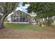 Rear exterior view of a home showcasing a spacious sunroom and a well-maintained backyard at 1209 Barcelona Dr, The Villages, FL 32159