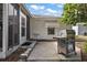 This back patio features a barbeque, an entry door to the screened-in back porch, and outdoor seating area at 1209 Barcelona Dr, The Villages, FL 32159