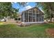 The screened-in back porch features plenty of windows and views of the manicured lawn with mature trees at 1209 Barcelona Dr, The Villages, FL 32159