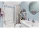 Cozy bathroom featuring a shower-tub combination, decorative mirror, and blue accent walls at 12221 Helena Ct, Leesburg, FL 34788