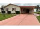 A quaint home featuring a carport with red doors and a salmon-colored driveway at 1234 E Schwartz Blvd, Lady Lake, FL 32159