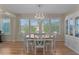 Sunlit dining area with a chandelier, elegant table, and views of lush greenery at 1508 Lakewood Dr, The Villages, FL 32162