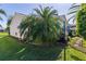 Exterior side view of a home showcasing lush landscaping, with mature palm trees and green lawn at 1508 Lakewood Dr, The Villages, FL 32162