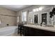 Stylish bathroom featuring a bathtub, a vanity with a sink, and a patterned tiled wall at 15307 Petrus Ln, Clermont, FL 34714