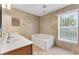 Bright bathroom with a soaking tub and large window, offering natural light and a relaxing atmosphere at 16456 Meredrew Ln, Clermont, FL 34711