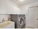 Functional laundry room with white cabinets, a utility sink, and modern washer and dryer at 1732 Madero Dr, Lady Lake, FL 32159