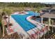 Aerial shot of the community pool featuring multiple swimming areas, lounge chairs, and lush landscaping at 17369 Blazing Star Cir, Clermont, FL 34714