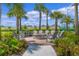 A community fire pit area with stone surround and ample Adirondack-style seating under the shade of palm trees at 17369 Blazing Star Cir, Clermont, FL 34714