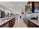 Open-concept kitchen with dark wood cabinetry, granite countertops, island seating, and a view into the living space at 17369 Blazing Star Cir, Clermont, FL 34714