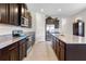 A bright kitchen featuring dark wood cabinets, granite countertops, tile flooring, and stainless steel appliances at 17369 Blazing Star Cir, Clermont, FL 34714