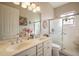 Bright bathroom with double sinks, shower, and decorative stained-glass window at 21051 Royal St Georges Ln, Leesburg, FL 34748