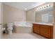 Bright bathroom featuring a soaking tub, wood vanity, and tile flooring at 2214 Lake Pointe Cir, Leesburg, FL 34748