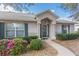 Charming home entrance with manicured landscaping, decorative shutters, and a welcoming front door with sidelights at 2256 Lake Pointe Cir, Leesburg, FL 34748