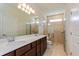 Bathroom featuring a double sink vanity, large mirror, and a glass-enclosed shower at 2365 Palm Park Loop, Clermont, FL 34714