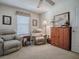 Cozy bedroom featuring two leather recliner chairs, natural light, and a storage cabinet at 2506 Greenhill Trl, The Villages, FL 32162