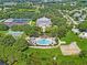 Stunning aerial view of a resort-style clubhouse, pool, and tennis courts surrounded by mature trees and lush landscaping at 25546 Belle Alliance, Leesburg, FL 34748