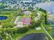 Aerial view of a recreational community hub with tennis courts, pool, and clubhouse surrounded by mature trees and a pond at 25546 Belle Alliance, Leesburg, FL 34748