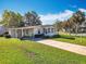 Inviting single-story home with a covered carport, featuring a well-manicured lawn and mature trees at 25546 Belle Alliance, Leesburg, FL 34748