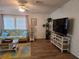 Well-lit living room featuring a patterned futon, wood flooring, and a large television at 263 Pinewood Dr, Eustis, FL 32726