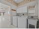 Bright laundry room includes white cabinets, sink and appliances at 321 Ranchwood Dr, Leesburg, FL 34748