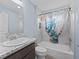 Bright bathroom with a granite vanity and a tub-shower combo with nautical-themed curtain at 3318 Dzuro Dr, Oxford, FL 34484