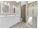 Modern bathroom with double sink vanity, stone countertops, tiled floors, and a glass-enclosed shower at 4324 Leafway Cir, Leesburg, FL 34748