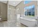 Bathroom displays a luxurious soaking tub beneath a bright window, next to glass enclosed shower at 4324 Leafway Cir, Leesburg, FL 34748